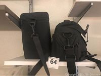Two black soft carrying bags side by side on shelf with lot number tag