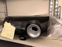 Black Planar DLP projector with lens on front, placed on a shelf with a note 'lot 606'