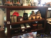 Front view of wooden shelving unit with various boxed items on shelves not included in sale.