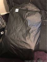 Black zippered protective coat bag laid flat, exterior view, labeled '104'