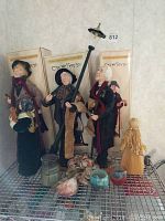 Photo showing three Jacqueline Kent Collection caroler figurines, each with boxes behind them, along with three small candles placed in front.