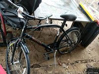 Black Brentwood KHS cruiser style bicycle with curved frame and padded saddle in outdoor setting with visible dirt and wear.