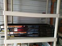 Overview image of two stacked black trailer ramps with visible warning stickers and identification label.