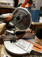 Side view of the Ridgid miter saw showing the blade and part of the manual underneath.
