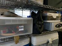 Shelf containing the clear plastic shoe storage bin labeled "shoes", Herbalife bag, and the boxed SurgeX power protection unit along with the APC power conditioner below it.