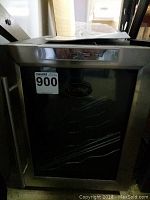 Front view of the Vinotemp wine cooler, showcasing stainless steel framing and glass door with visible interior rack space for wine bottles.