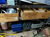 View of three wooden wine boxes on metal shelf containing various tools, cords and storage items