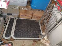 Full view of the metal wheeled utility cart, showing black rubber platform and metal handle with rust spots.