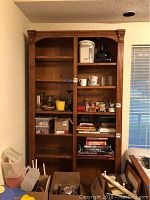 Full front view of wooden shelving unit with assorted items on shelves, showing overall size and design.
