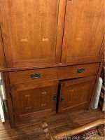 Front view of entertainment center showing two drawers above two cabinet doors with butterfly joint details and metal hardware.