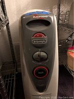 Front view of silver DeLonghi Rapido oil-filled radiator heater showing control knobs and brand label.