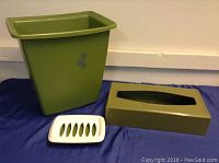 Photo showing the green waste bin, olive green tissue box cover, and white soap holder placed on a blue cloth.
