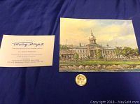 Photo showing the print and accompanying artist's card on a blue fabric background with a small coin for scale.