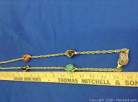 Full length of necklace on blue background with measuring ruler showing approx 32 inches length