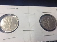 Photo showing obverse and reverse of 1945 and 2005 Canadian Victory nickels, housed in cardboard holders.