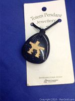 Blue goldstone teardrop pendant with gold Inukshuk engraving on black cord, displayed on product card.