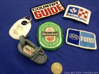 Photo of keychains and patches arranged on blue cloth with coin for scale.