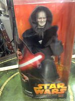 Front view of Darth Sidious figure in packaging showing figure details, lightsaber, box with Star Wars logo.