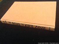 Closed hardcover book with beige spine showing the title 'The Road to Kips Cove' by Lynn Cook.