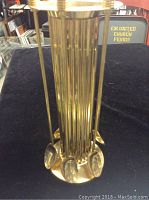 Set of six long metal spoons in a matching metal holder with a cylindrical design.