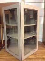 Front and side view of the wooden display case showing glass panels on two visible sides and overall structure.