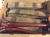 Box containing rough wooden barrel slats and two finished smooth dark wood legs.