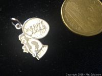 Close-up photo of the front of the sterling silver Christmas charm showing 'Merry Christmas' plaque and raised Santa Claus figure alongside a coin for size reference.