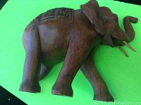 Side profile of the large carved wooden elephant showing trunk raised and carved saddle detail.