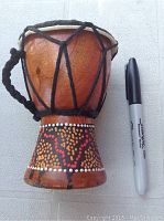 Front side photo of mini bongo drum with decorative dotted painted base, black rope tuning and a Sharpie for size reference.