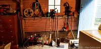 Wide shot showing garden tools including spade, shovel, rake, Toro electric trimmer hung on wall, and assorted items