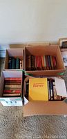 Photo of three boxes filled with vintage books from various authors including look at worn colorful spines