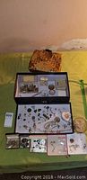 Overview of assortment jewelry lot including multiple pieces arranged in trays and a woven box container.