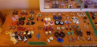 Photo of assorted costume jewellery earrings laid out on a flat surface arranged in pairs of various styles, colors, and sizes.