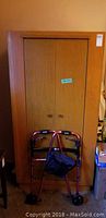 Photo of vintage wooden wardrobe with bifold doors and Drive metal walker placed in front.