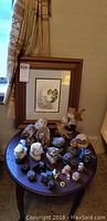 Front view showing framed signed original Sue Coleman owl artwork and numerous owl figurines on round table.