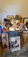 Wide shot of table with decorative figurines, framed artworks, and other decorative items.
