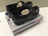 Side and top view of the black Skechers slip-resistant work shoes placed on their original box showing new condition.