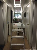 Front view of the full 8 foot aluminum step ladder positioned in a hallway.