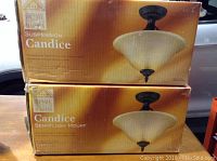 Two boxed suspension light fixtures with bronze finish and frosted glass shades, labeled Candice by Home Trends