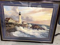 Framed lighthouse coastal scene with waves and house in dark frame