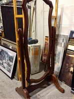 Full view of the wooden framed floor mirror with a uniquely shaped rectangular glass and curved edges.