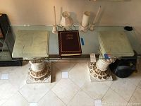 Full top view of glass table showing rectangular glass surface and two ornamental column supports beneath.