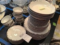 Overall view of stacked plates, cups, saucers on table showing full set
