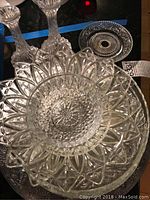 Nine pieces displayed showing cut glass bowls and platters on top of a silver plated tray with embossed pattern.