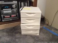 Stereo system with 3-disc changer and speakers next to small white 4-drawer cabinet.