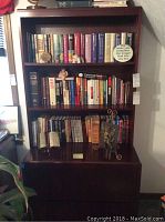 Front view of the cherry wood bookshelf filled with books and decorative items on shelves.