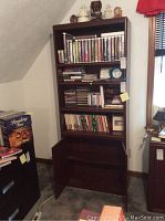 Full frontal view of the tall bookshelf filled with books and other items, showing four shelves.