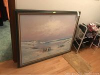 Framed large canvas painting showing the entire artwork leaning against a wall with floor visible and part of a shoe rack next to it.