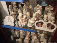 Shelf showing 14 Precious Moments figurines and photo frames in soft pastel colors and mint condition.