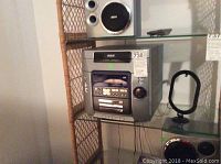 Photo showing RCA 5-disc boom box stereo unit with front panel controls and cassette player inside a shelf unit.